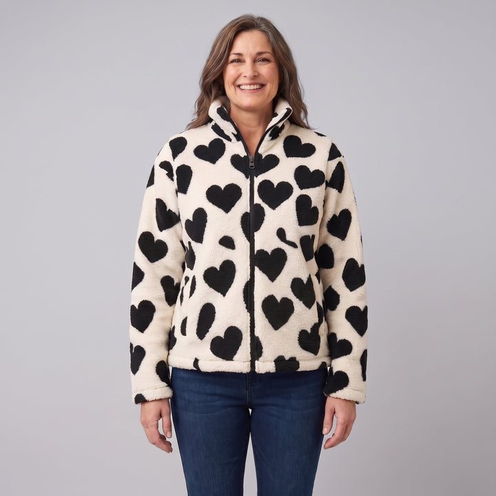 Woman wearing a cream sherpa jacket with black hearts, front view