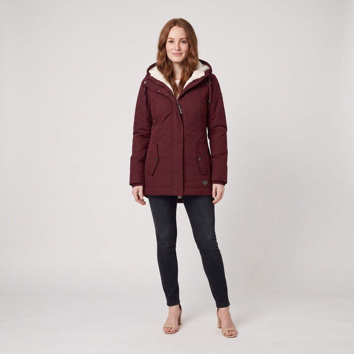 Woman wearing a dark red fleece-lined hooded parka, front view