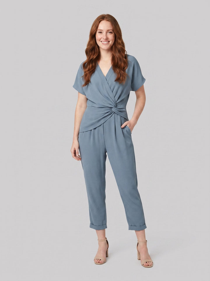 Lyra draped knot jumpsuit in dusty blue, wrap V-neck with knotted waist, front view on model